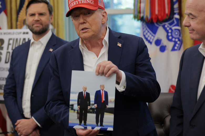 Дональд Трамп держит фотографию, на которой он запечатлен с президентом России Владимиром Путиным на Аляске