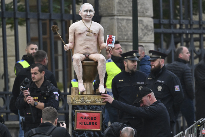 Протестующие у Пражского Града демонстрируют фигуру президента России Владимира Путина, сидящего на золотом унитазе, на Европейском саммите в Праге 7 октября 2022 года