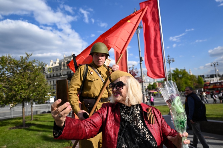 Женщина делает селфи с артистом в советской военной форме на праздновании Дня Победы в центре Москвы