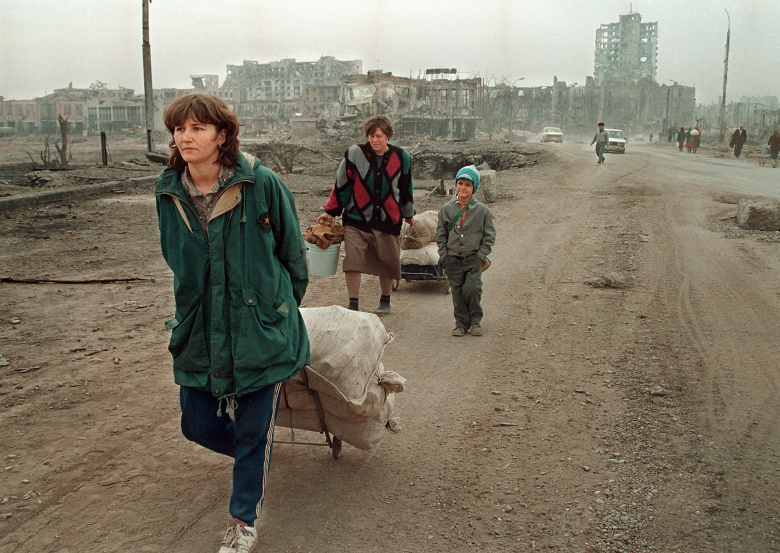 Женщины тянут тележки на разрушенных улицах Грозного, 1995 год.