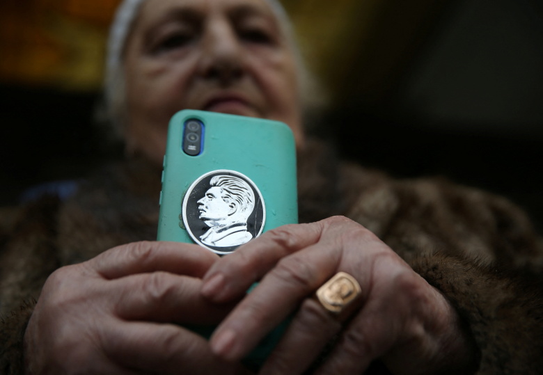 Женщина держит телефон с портретом советского лидера Иосифа Сталина на чехле во время мероприятия, посвященного 70-летию со дня смерти Сталина