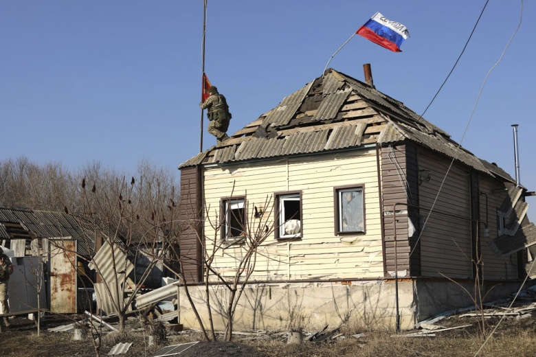 Суджа (Курская область), 14 марта 2025 года. После ухода ВСУ российский солдат поднимает красное знамя над зданием, над которым уже развевается российский флаг