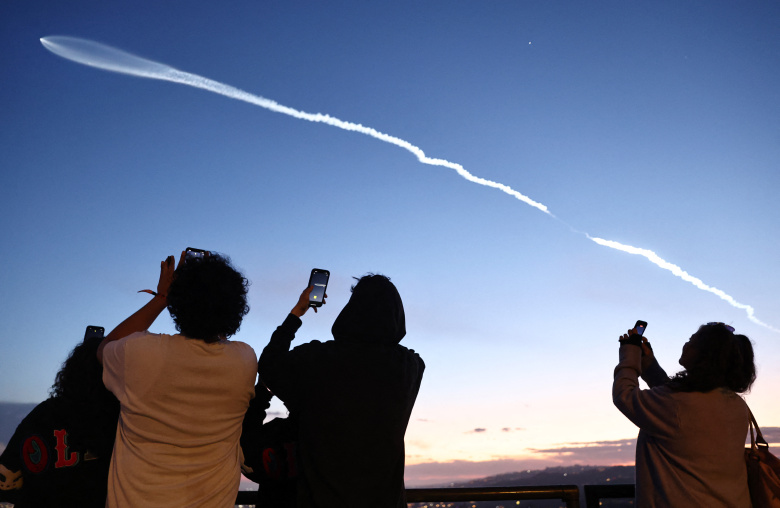 Люди наблюдают за ракетой SpaceX Falcon 9, несущей в космос полезную нагрузку из 22 интернет-спутников Starlink