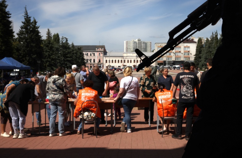 Охранник с оружием перед пунктом приема беженцев и раздачи гуманитарной помощи в Курске, 16 августа 2024 года