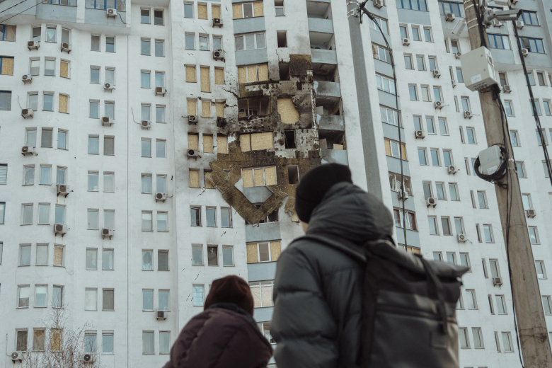 Двое людей осматривают поврежденное жилое здание после российской атаки на Киев рано утром 10 января 2026