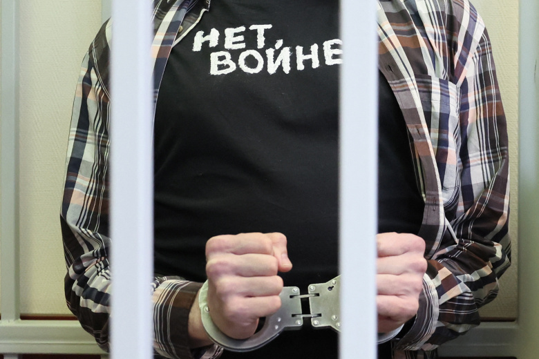 Российский журналист Роман Иванов в футболке с надписью «Нет войне» в наручниках в клетке для подсудимых, его судили за критику войны в Украине в социальных сетях